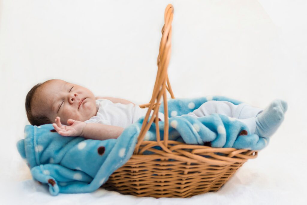a baby sleeping in a basket with a blanket
